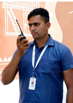 A.S.S. Security guard on walkie-talkie in blue shirt with ID lanyard